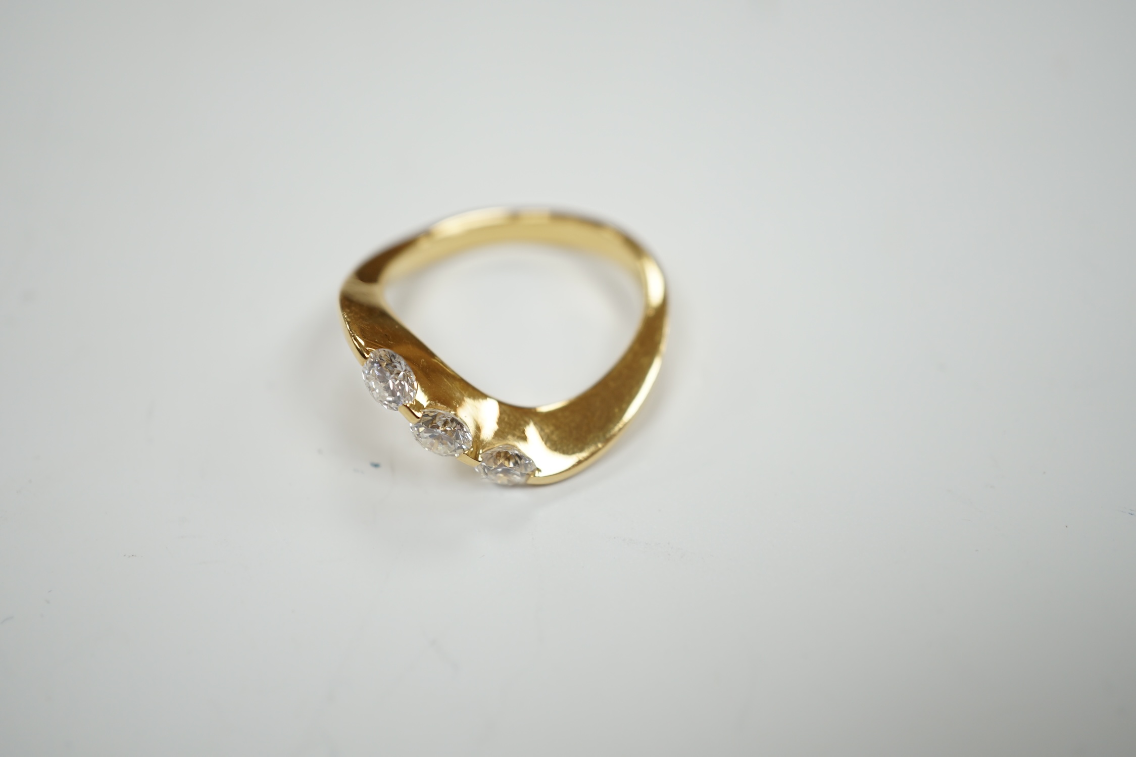 A modern 750 yellow metal and three stone diamond set crossover ring, size P, gross weight 5.4 grams.